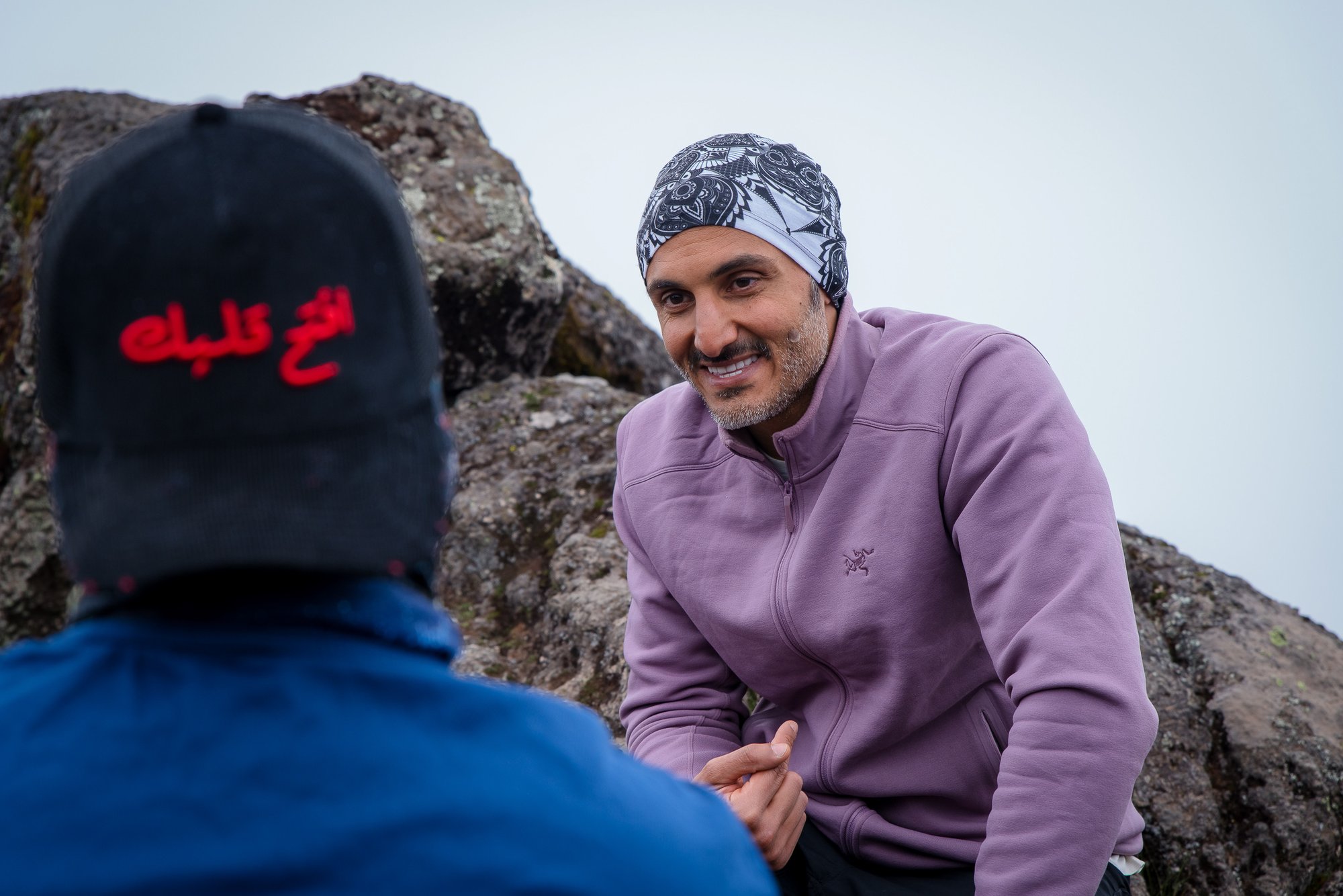 Moe laughing with a teammate, the Rahhalah cap turned back