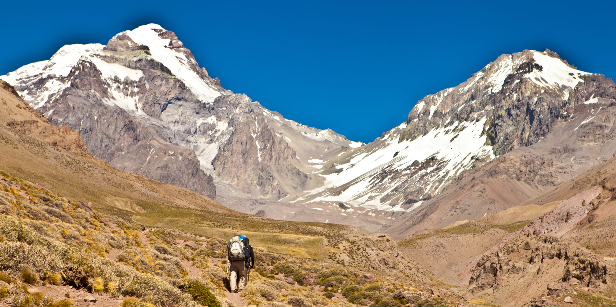 A lone hiker in a wide mountain valley