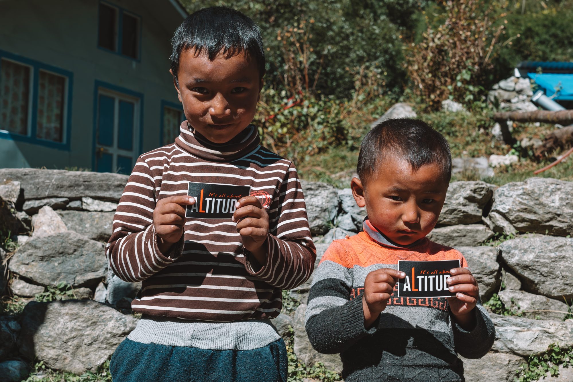 Two children in a mountain village holding cards