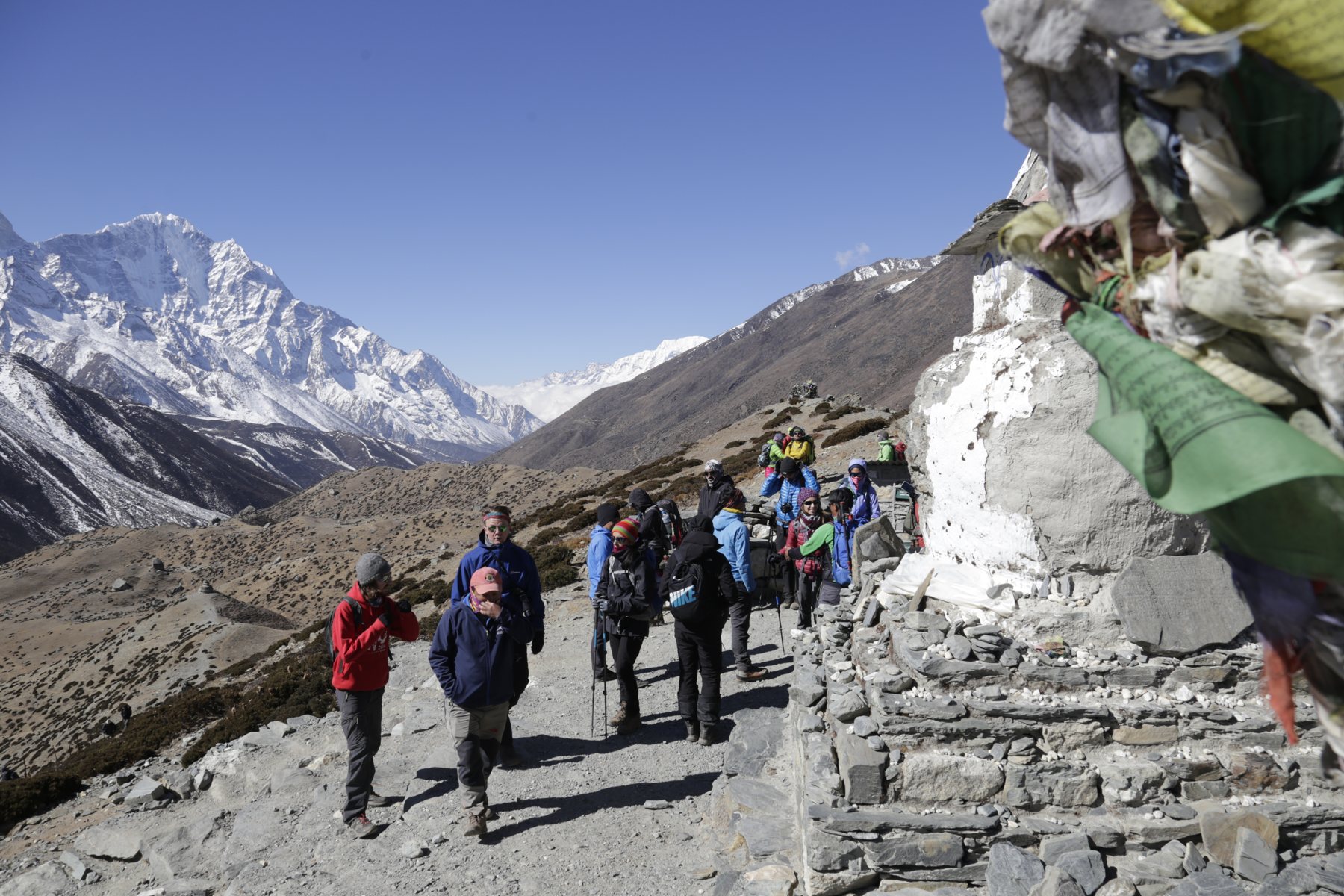 A group following the trail past a white stone monument