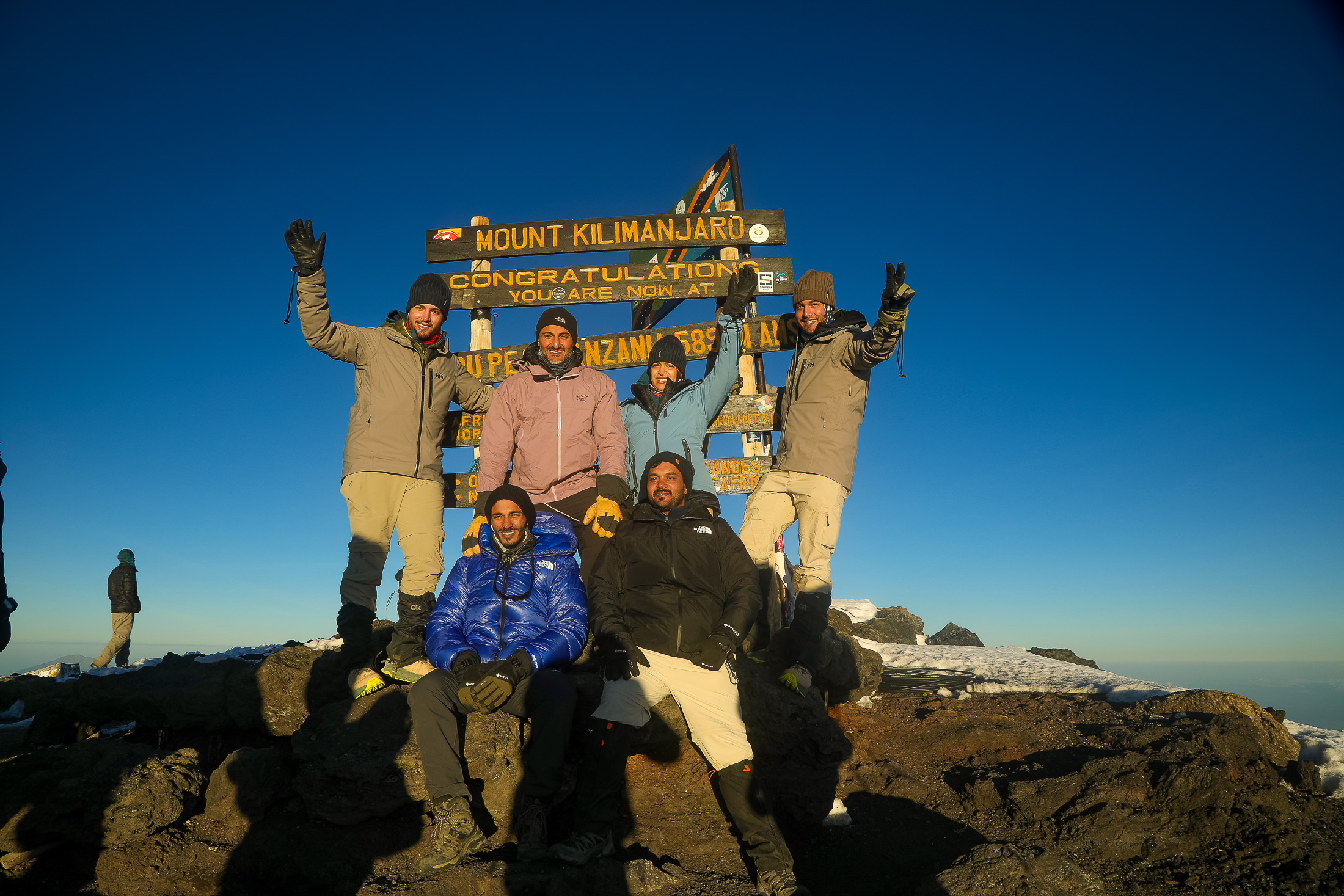 The team celebrating together at the Kilimanjaro summit sign