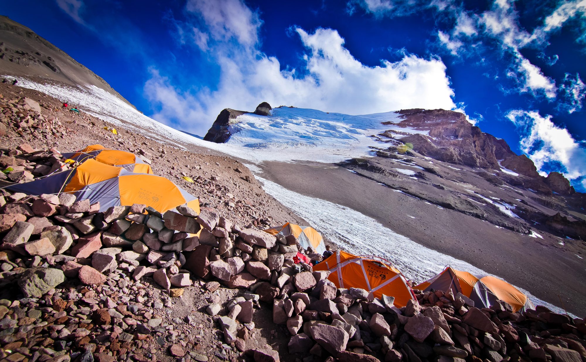 Tents pitched on a rocky slope under a dramatic sky