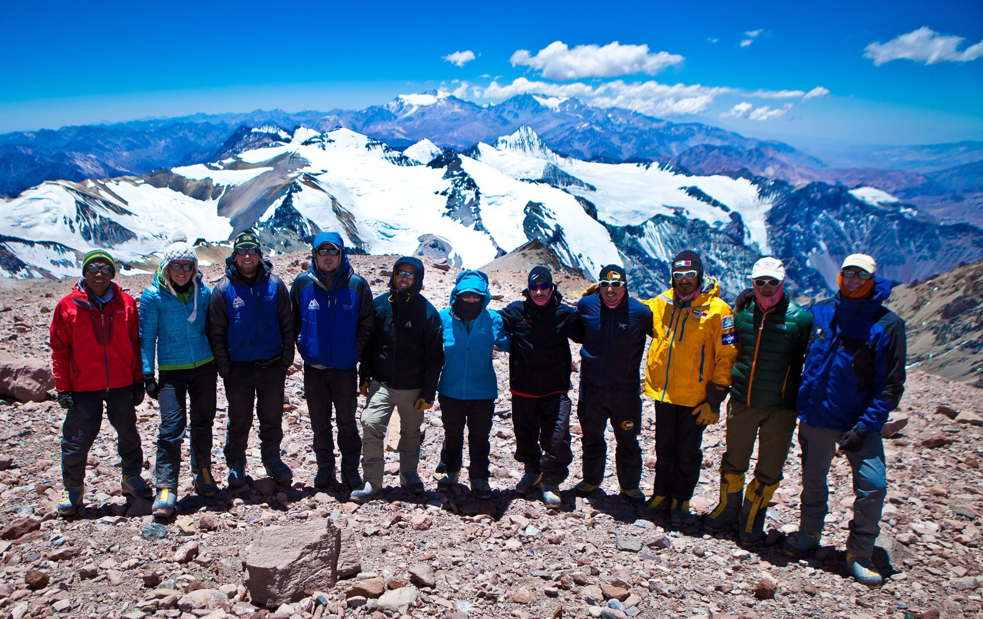 An expedition team standing together beneath snowy peaks