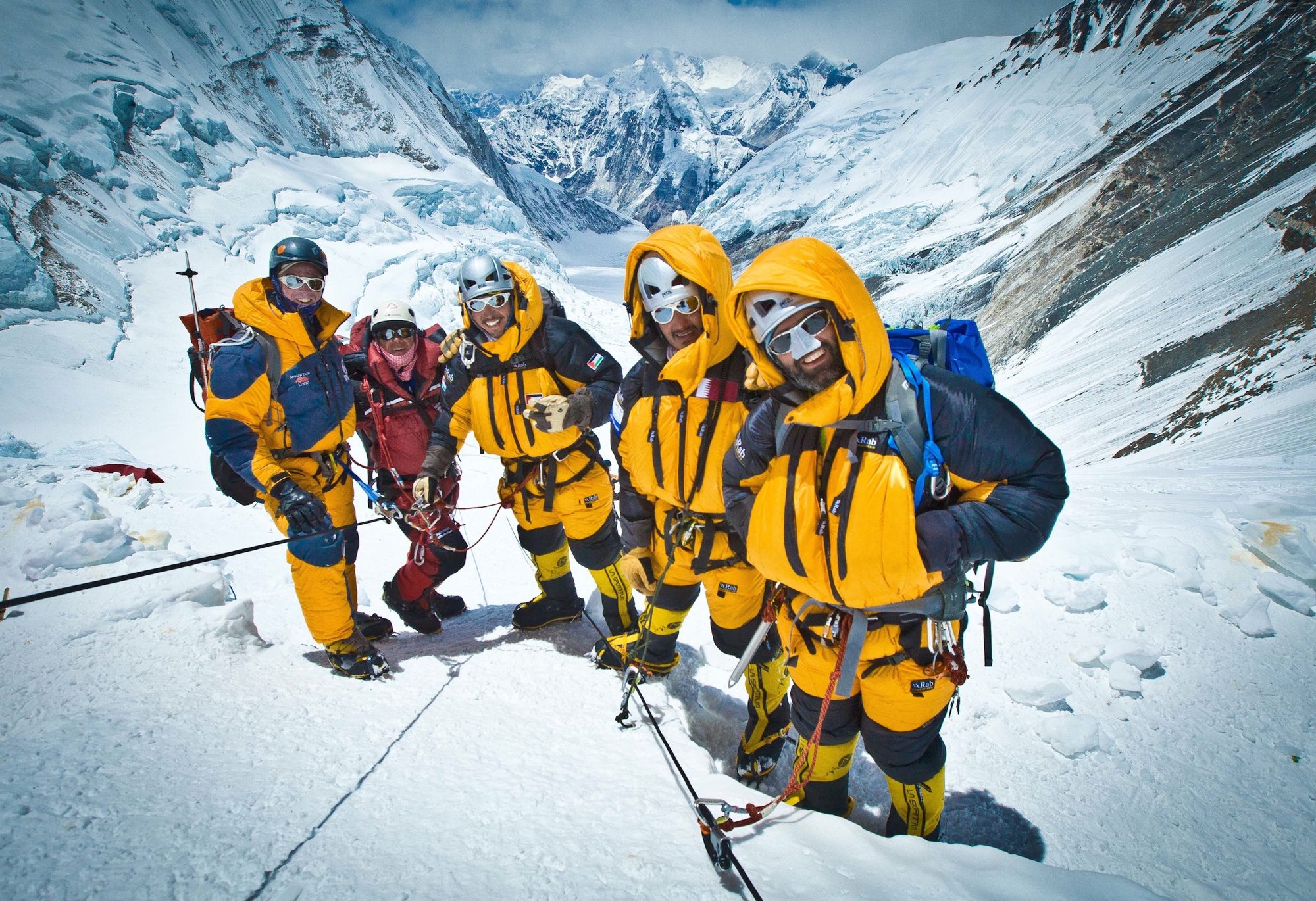 A roped team in down suits pausing on a snow slope