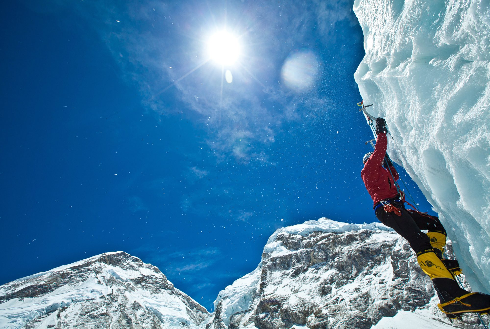 A climber on a wall of ice beneath the sun