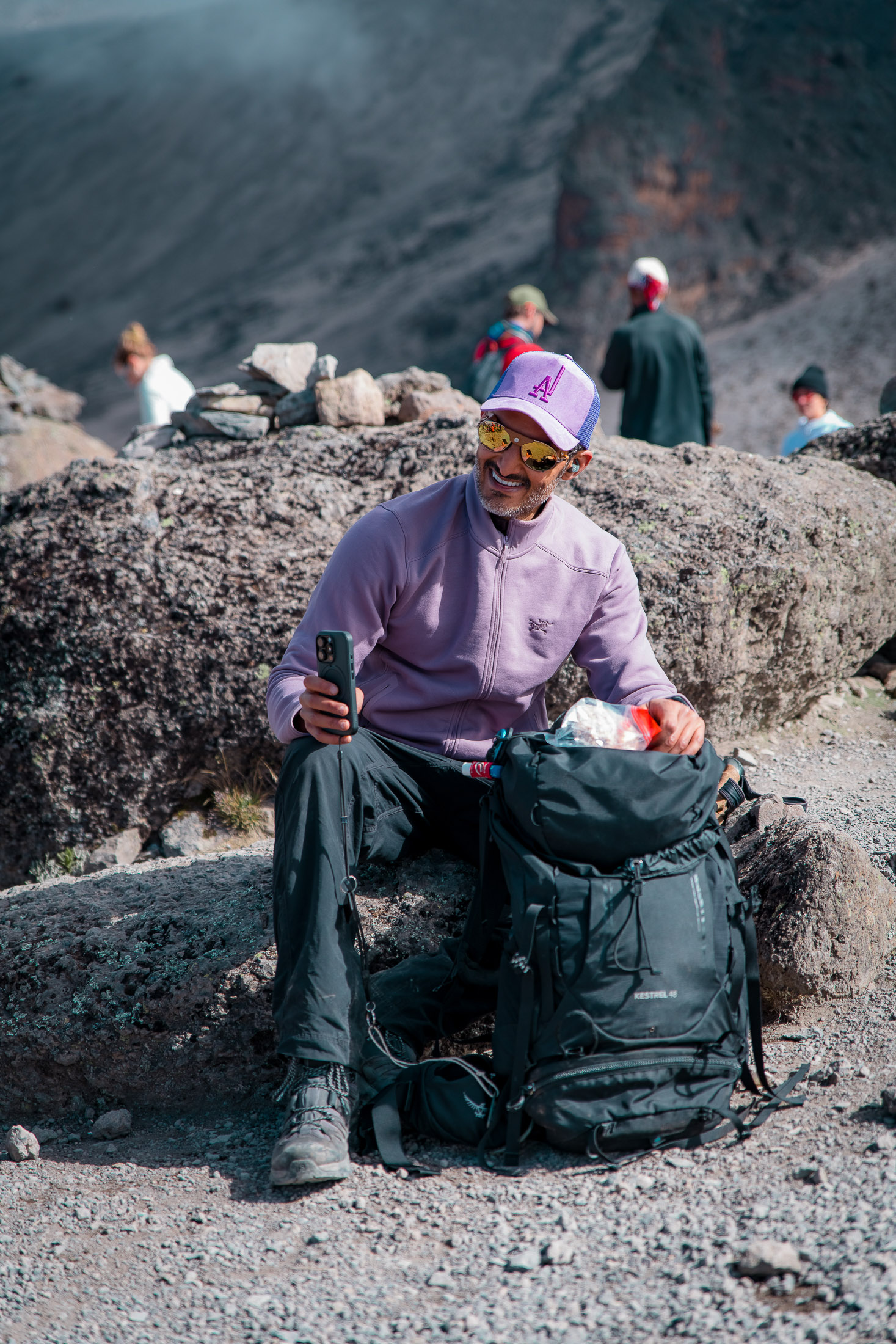 Moe resting with his pack on the rocky slopes of Kilimanjaro