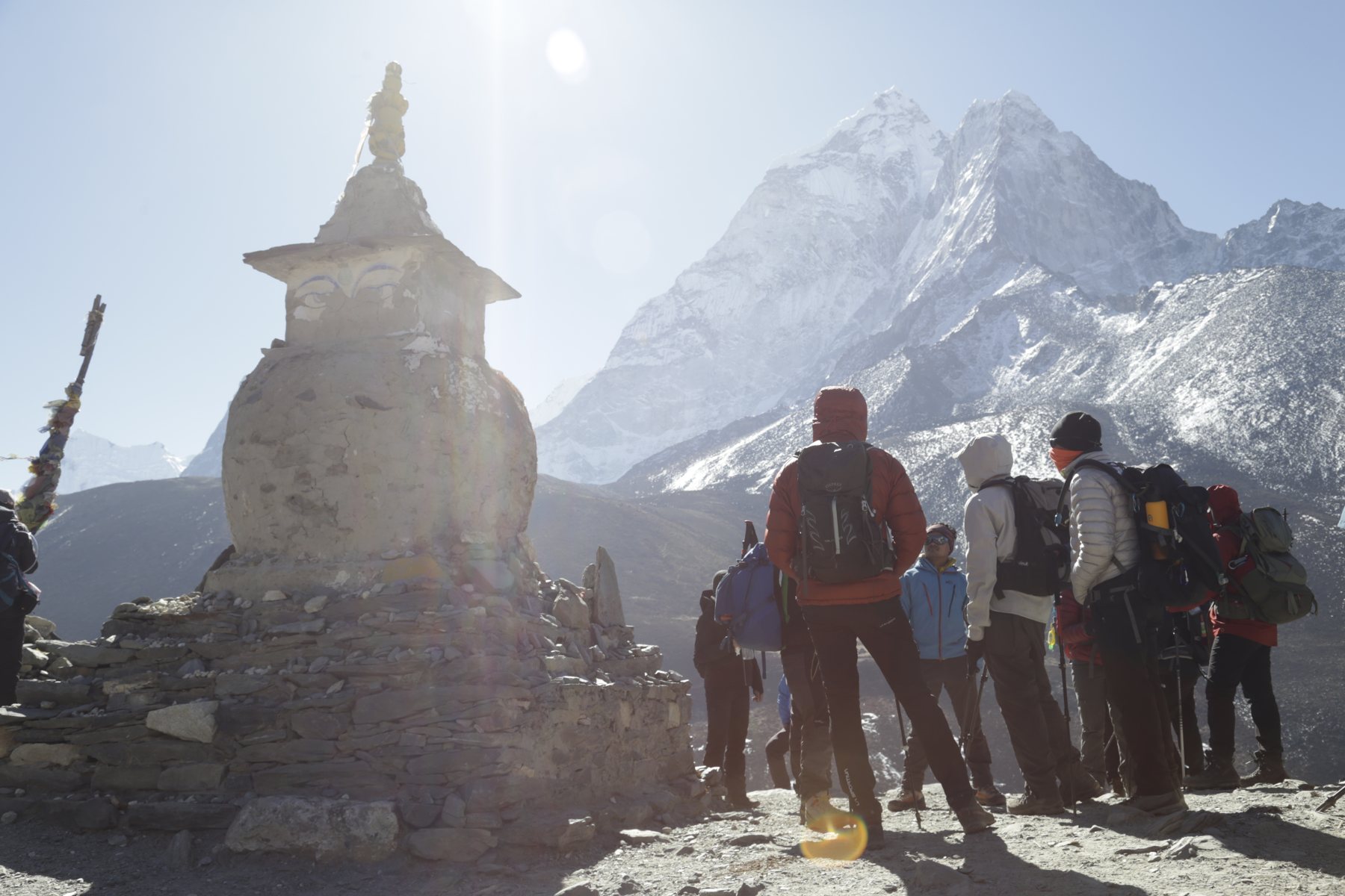 A group gathering beside a stone monument beneath snowy peaks