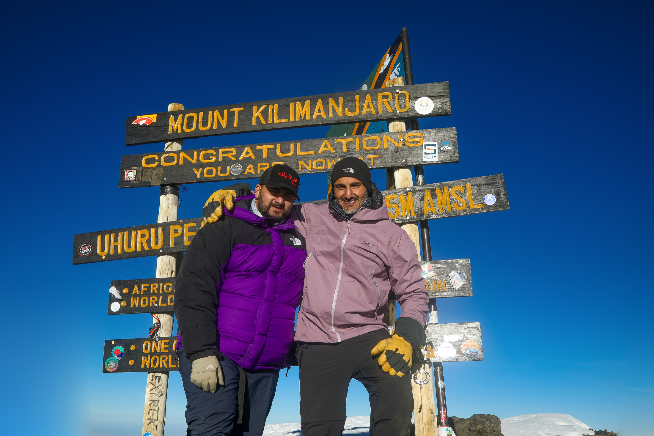 Moe and Joe Al Haddad at the Uhuru Peak summit sign on Kilimanjaro